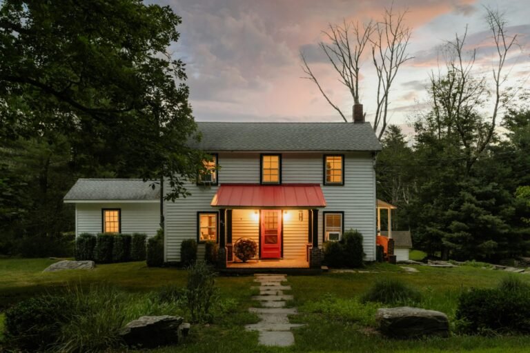 view of a white house with a red awning and bright lights, surrounded by trees
