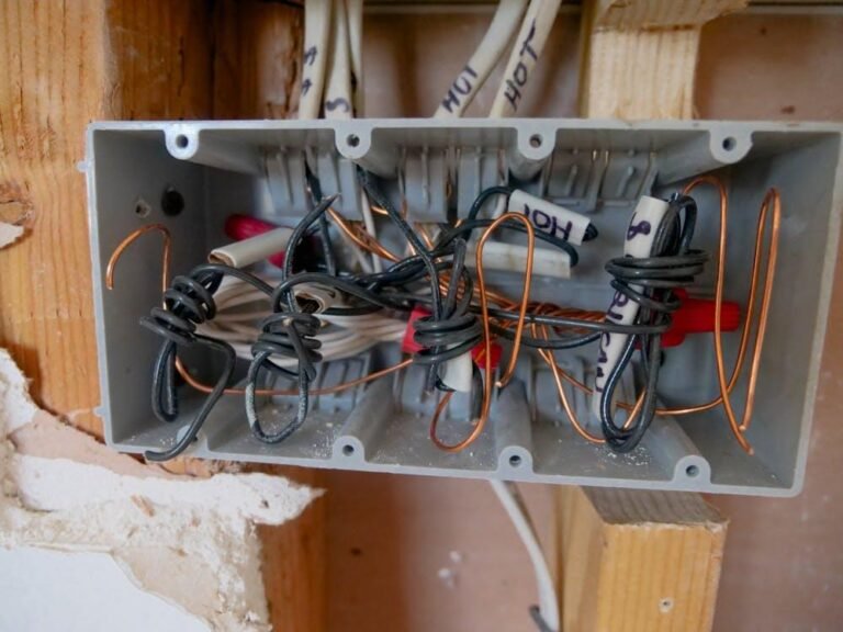 Overcrowded electrical junction box with improperly spliced wires inside a residential wall