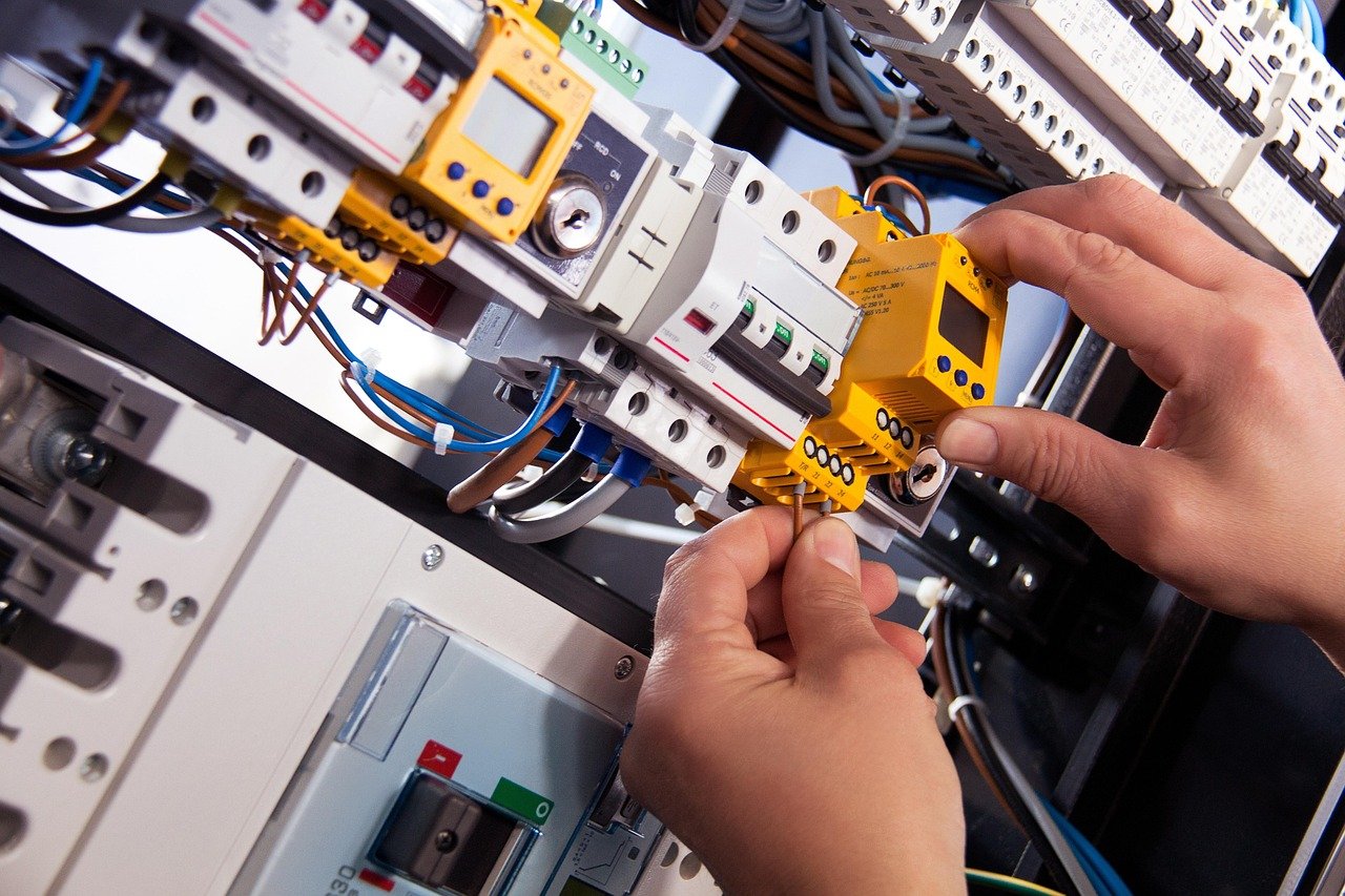 an electrician’s hand working on circuit breakers.