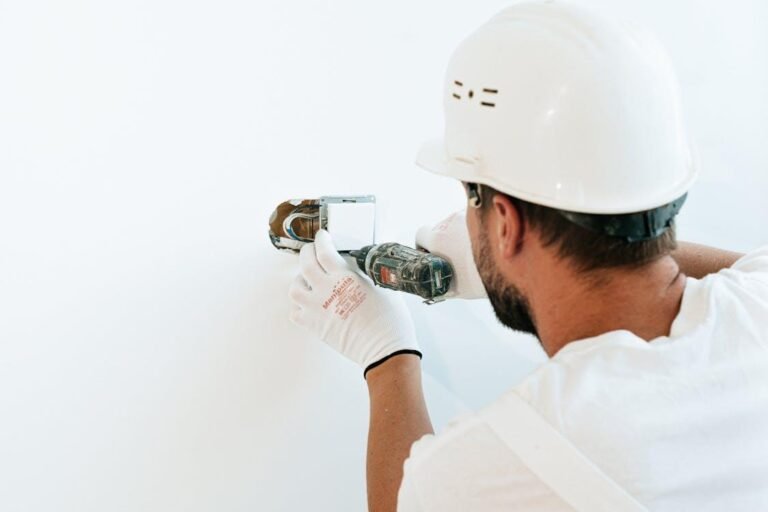 Electrician installing a wall outlet using a power drill