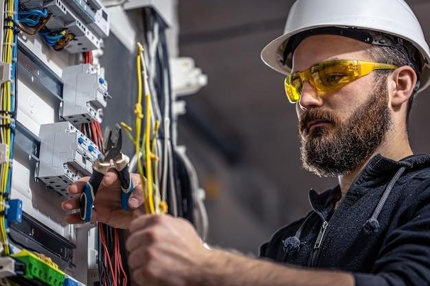 Electrician wearing safety glasses inspecting and repairing wiring inside an electrical panel