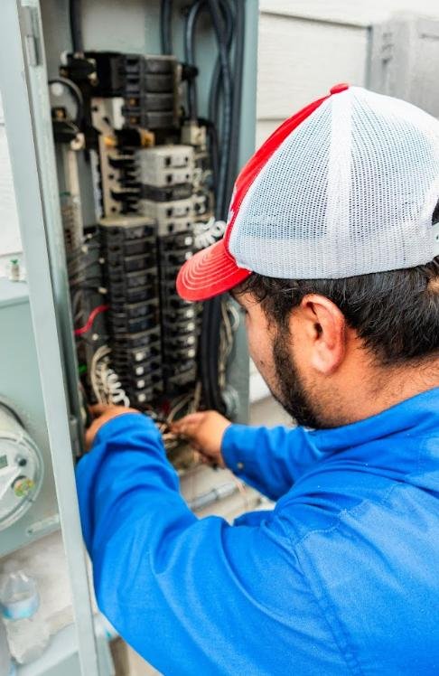 Electrician inspecting and working inside a residential breaker panel