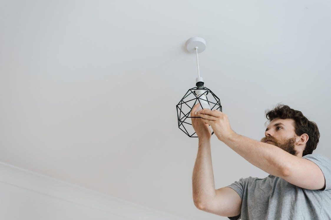 Electrician installing a ceiling light fixture during a residential repair