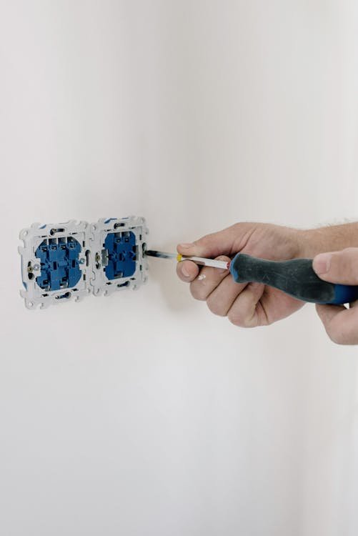 Technician installing dual electrical outlet boxes in a freshly painted wall
