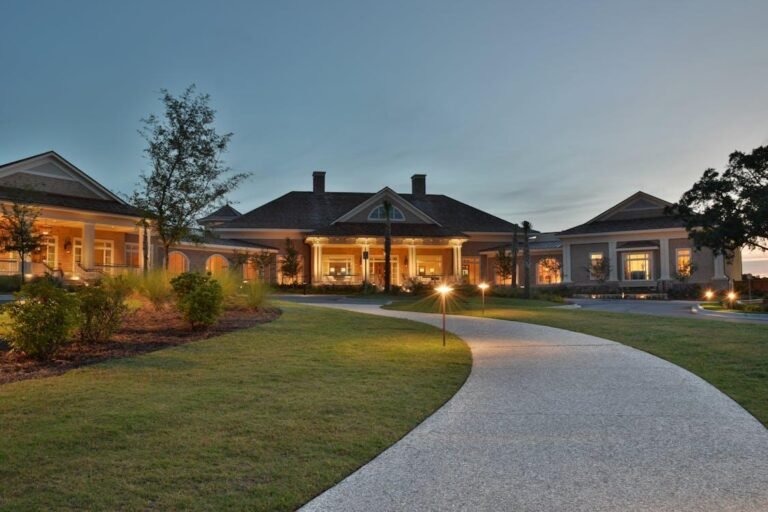Curved walkway leading to a luxury home illuminated by low-voltage landscape path lights at dusk